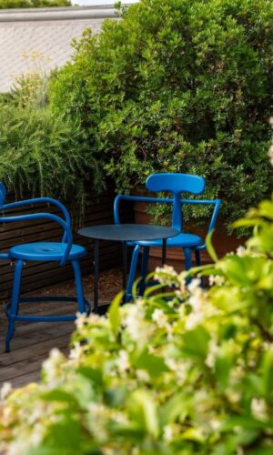 Fauteuil de jardin Nicolle fabriqué en France dans un jardin verdoyant.