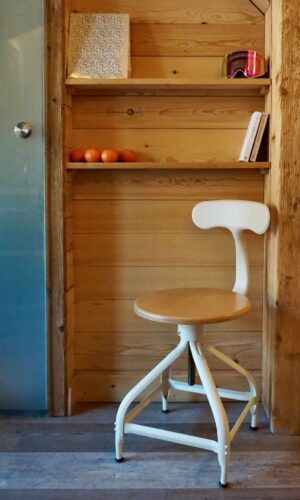 Chaise blanche moderne à côté d'étagères en bois.